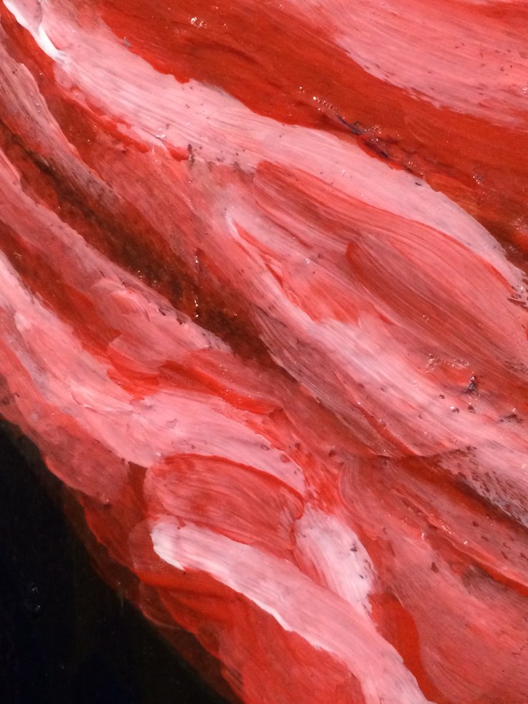 A close up of brushstrokes in reddish orange and pink.